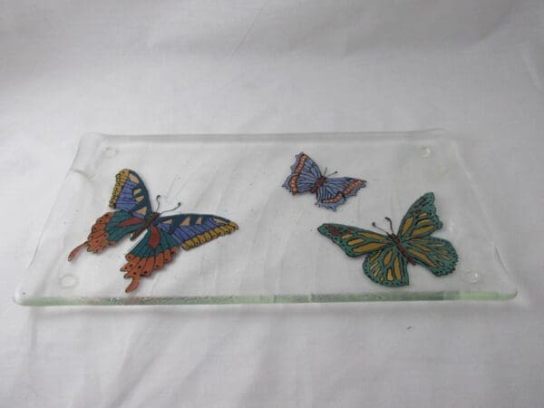 A hand-painted tray featuring three vibrant butterfly illustrations set against a simple white background.