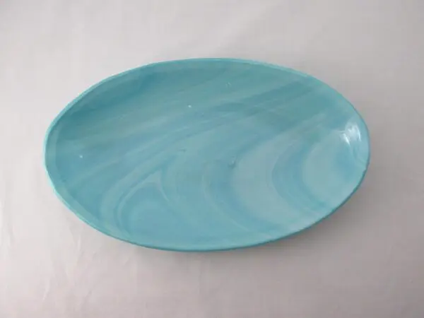 An aquamarine frost-colored ceramic plate with a marbled pattern on a white background.