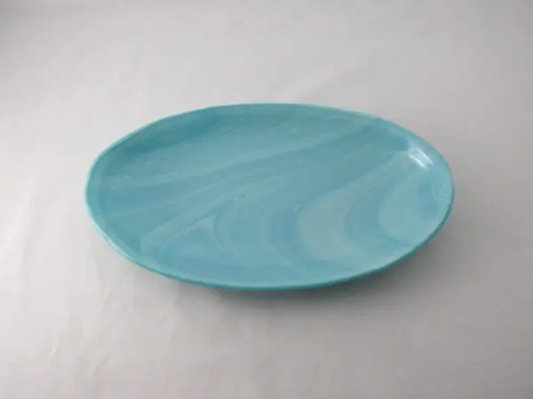 The OV18015 - Aquamarine Frost Oval Serving Dish, crafted from light blue ceramic and featuring a smooth, marbled design, sits on a simple white background.