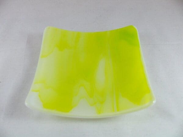 Here is a revision of the sentence using your specified product data:

A square, curved glass dish featuring a white and yellow marbled design on a plain background is the SP7020 - Spring Green Wispy Sushi Plate.