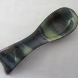 A green and black spoon rest sitting on top of a table.