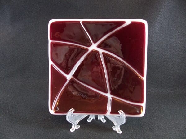 A square plate with a red and white design on top of it.