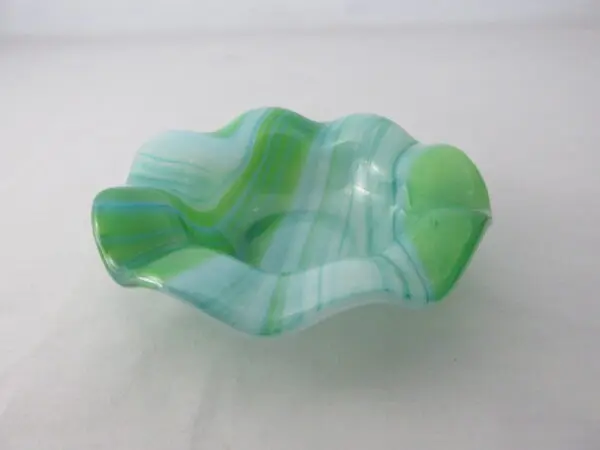 A green glass bowl sitting on top of a table.