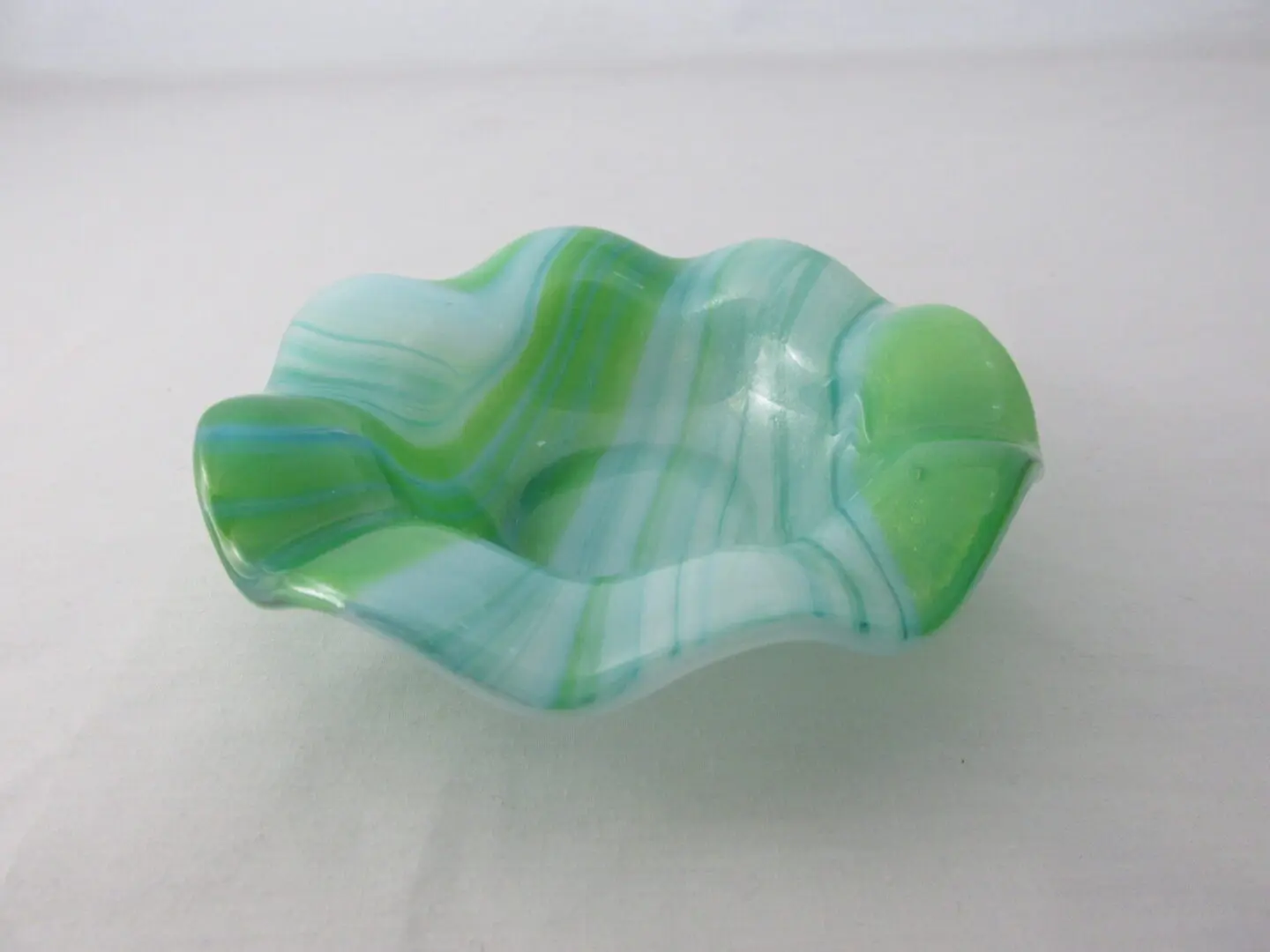 A green glass bowl sitting on top of a table.