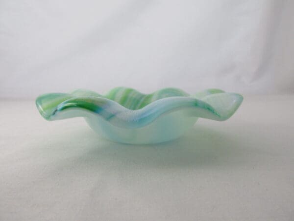 A glass bowl with green and blue swirls on it.