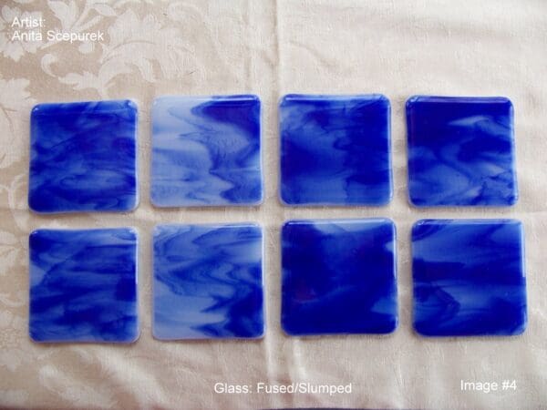 A set of eight blue glass coasters on top of a table.