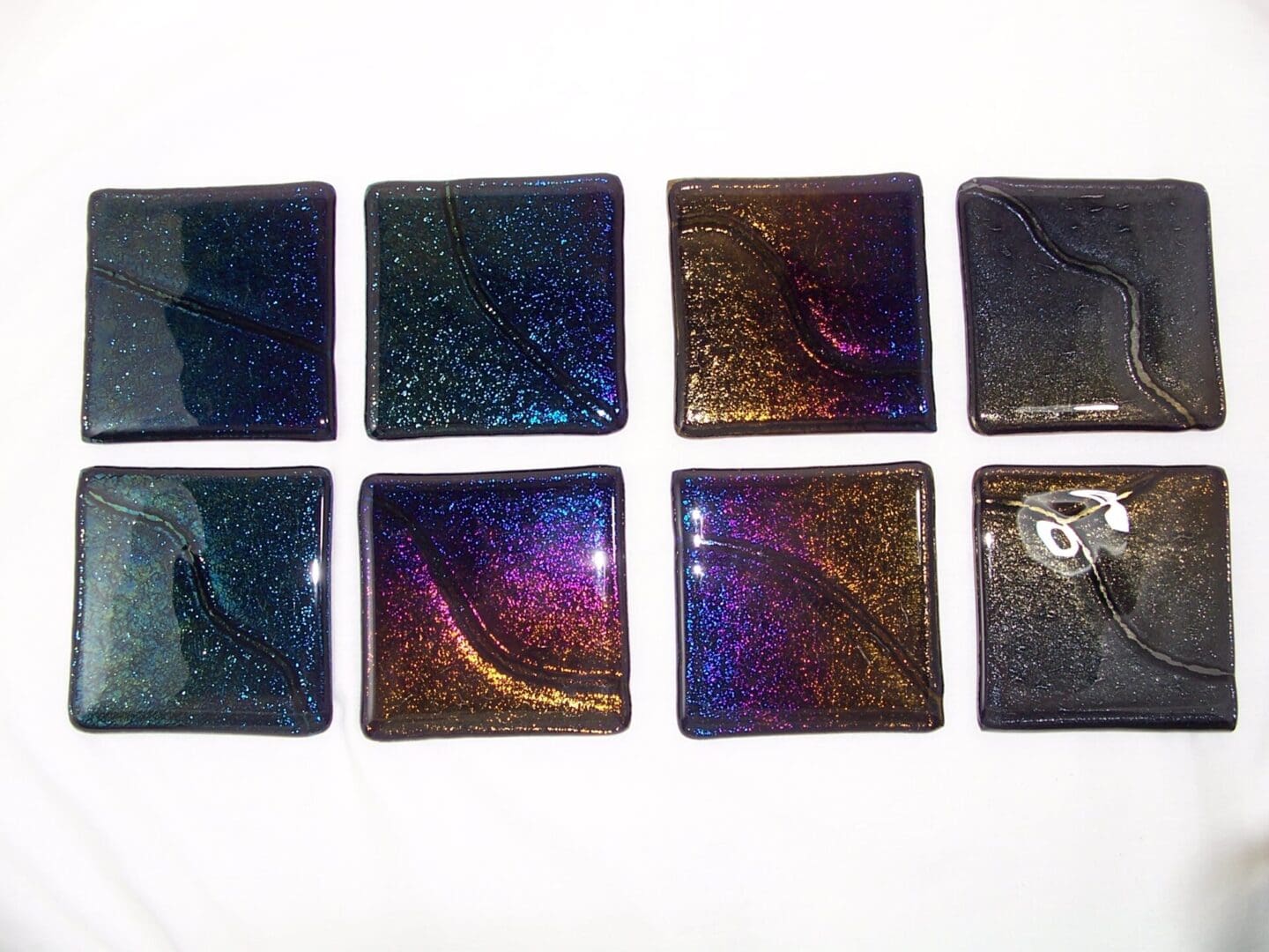 A group of eight square glass tiles in different colors.