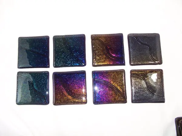 A group of eight square glass tiles in different colors.