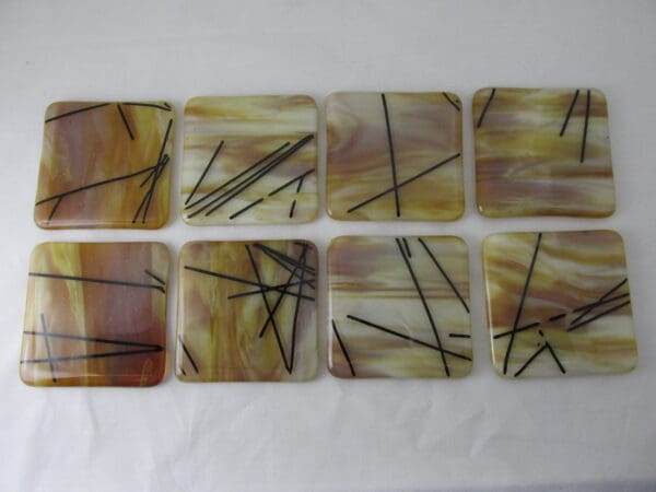 A set of eight coasters with brown and yellow designs.