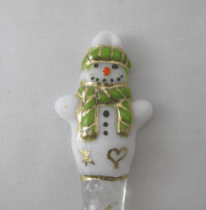 A white and green snowman ornament on a table.