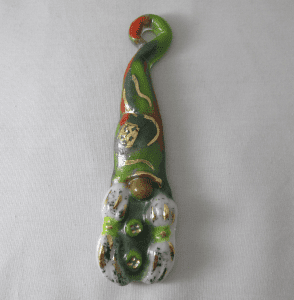 A green and red cat ornament on a white surface.