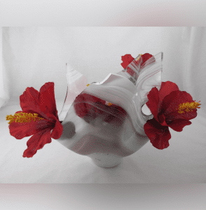 A white vase with red flowers in it.