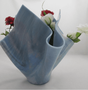 A blue vase with flowers in it on top of a table.