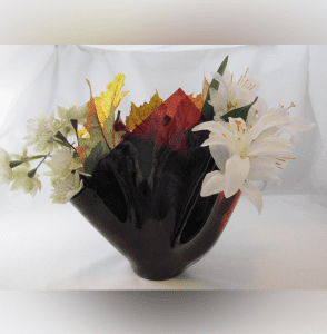 A black vase with flowers inside of it.