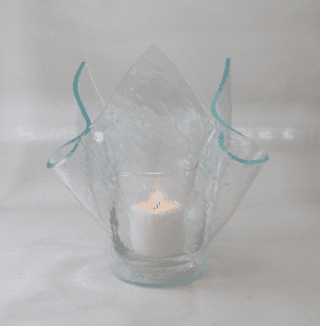 A candle in a glass vase with water on it.