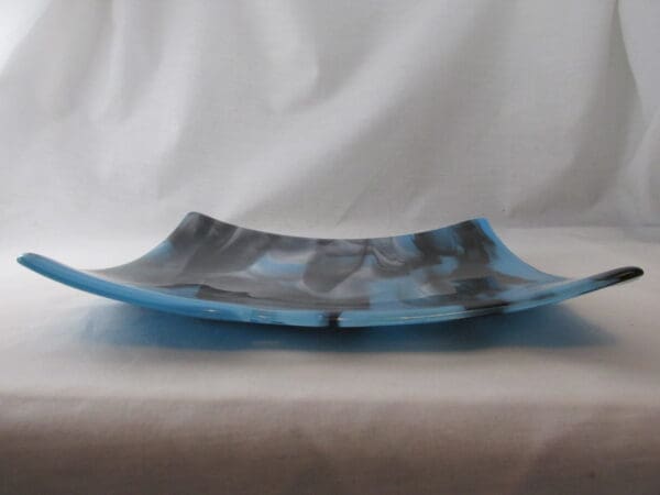 A blue and black glass plate sitting on top of a table.