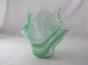 A green glass vase with some wavy lines on it