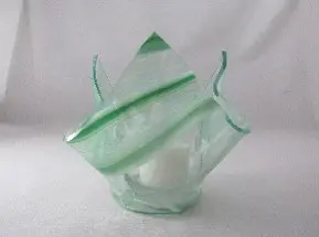 A green glass vase with a white candle inside.