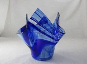 A blue glass vase with some folded up in it