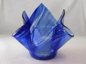 A blue glass vase with a folded up design.