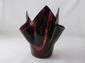 A red and black vase sitting on top of a table.