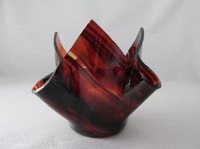 A red and black glass vase sitting on top of a table.