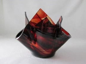 A red and black glass bowl sitting on top of a table.