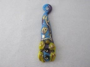 A blue and yellow glass bead with a face