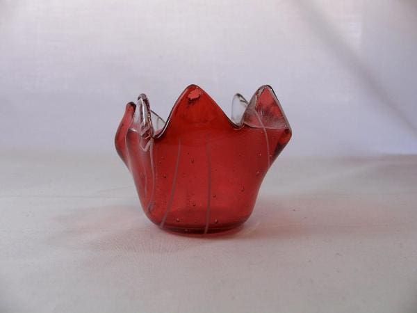 A red glass candle holder sitting on top of a table.