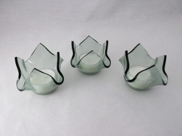 Three glass candle holders with a black trim.