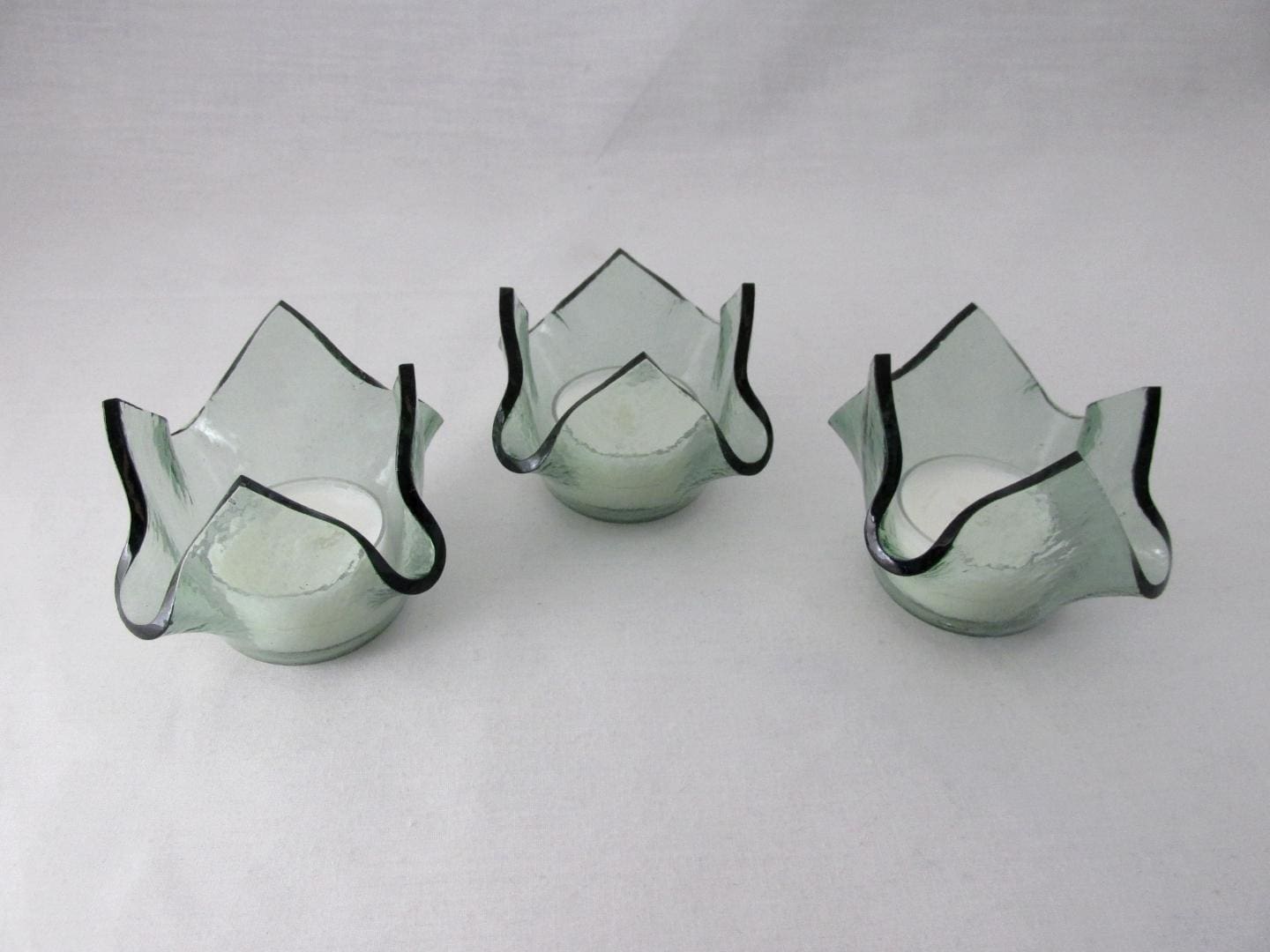 Three glass candle holders with a black trim.