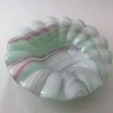 A glass bowl with green and pink stripes on it.