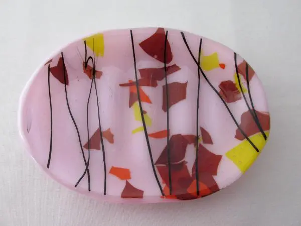 A pink plate with red, yellow and black leaves.