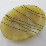 A yellow and black striped dish on top of white table.