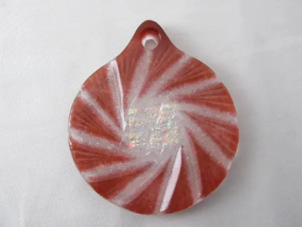 A red and white ornament with a swirl design.