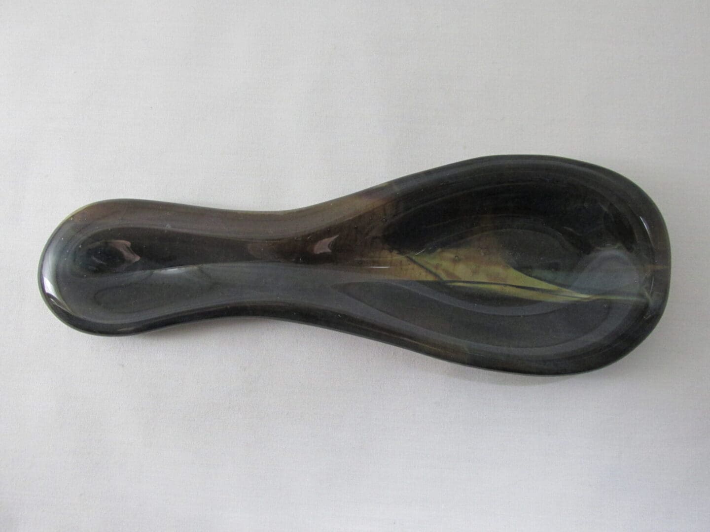Dark glass spoon on white background.