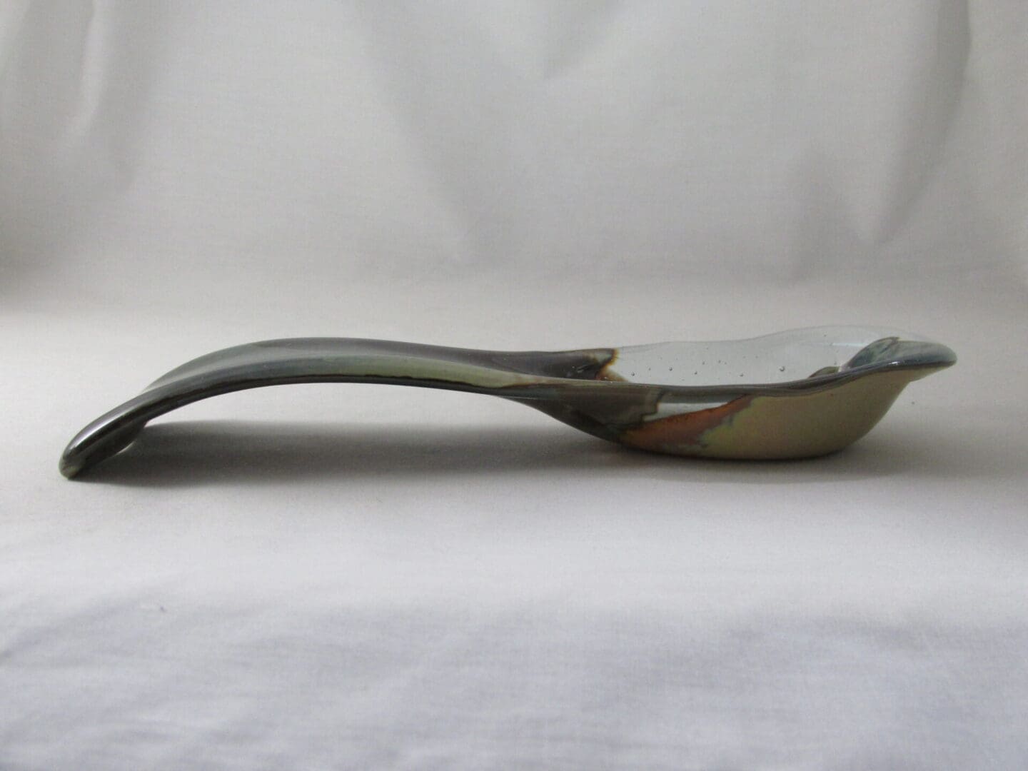 Ceramic spoon rest with curved handle.