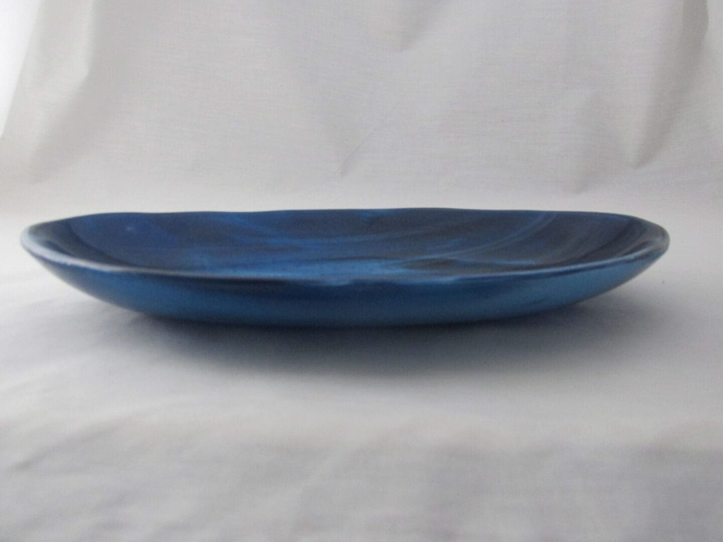 Shallow blue ceramic plate on white cloth