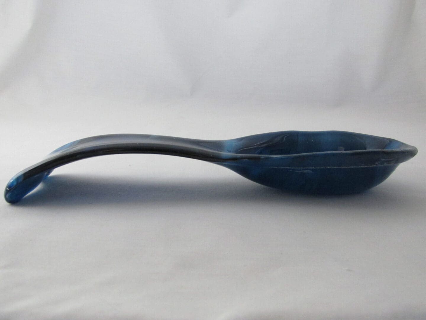 Glazed blue ceramic spoon on white background